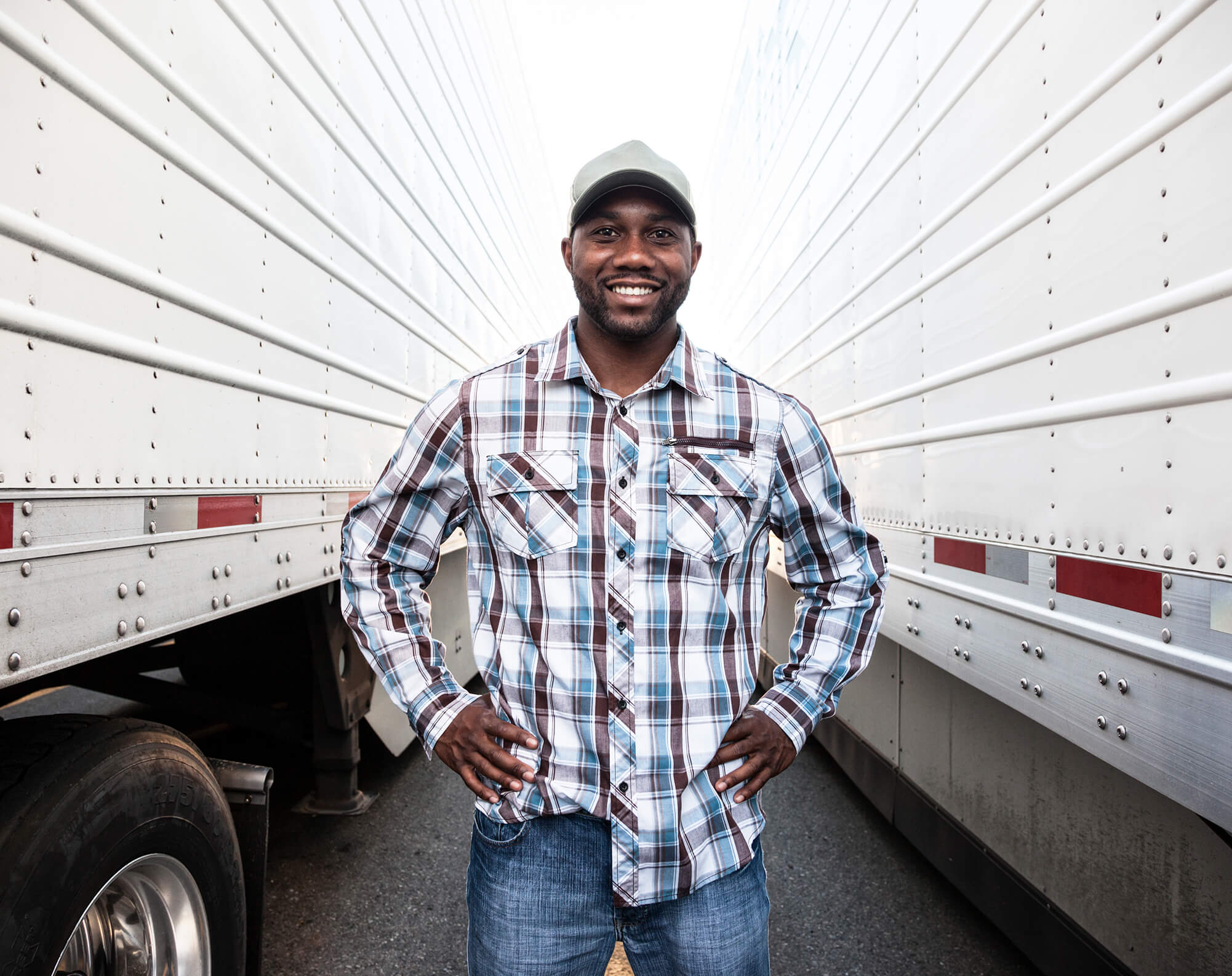 a man standing in between to tractor trailers smiling