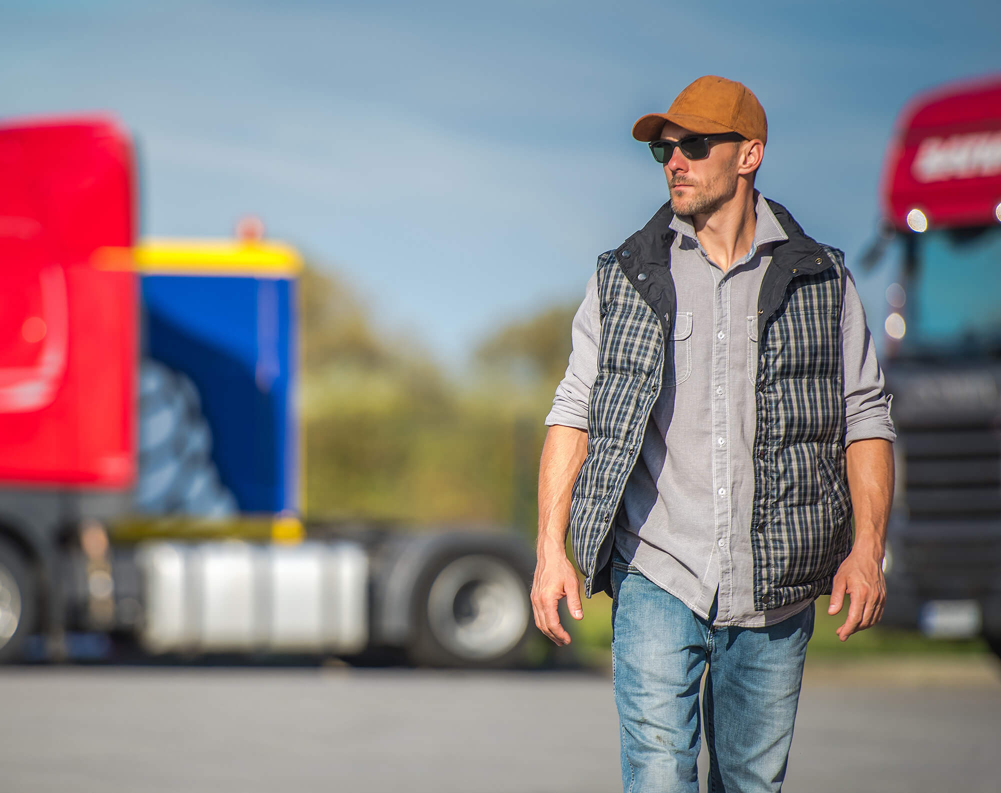 a man standing in the parking lot with semi trucks behind him