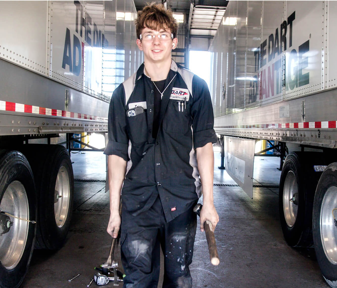 a young man working and standing between two DART semi-trucks